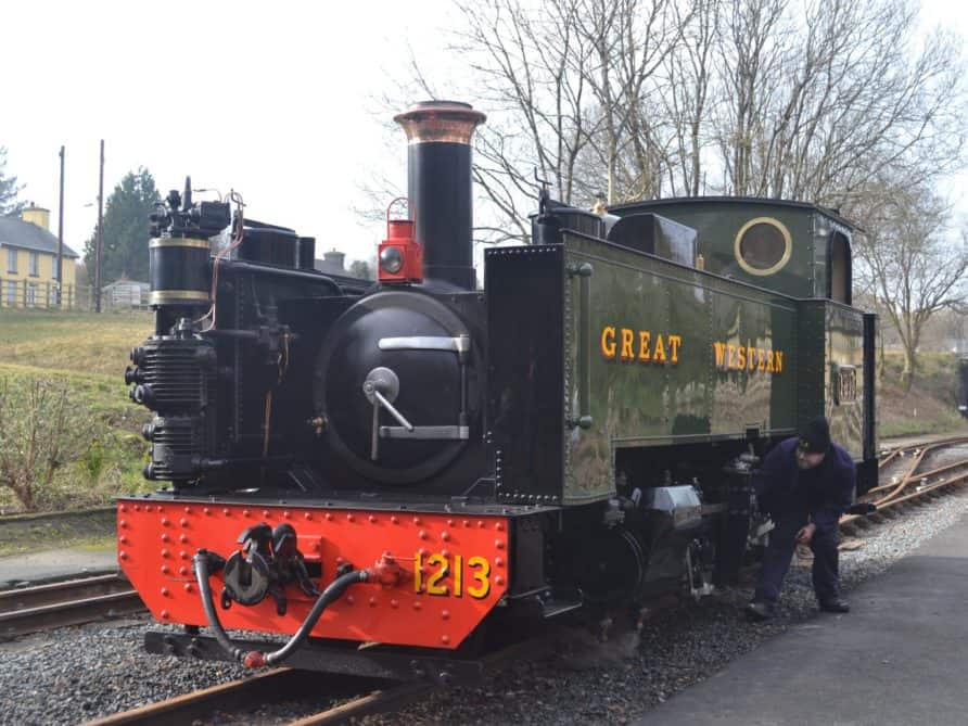 A narrow gauge steam engine being tended by the driver